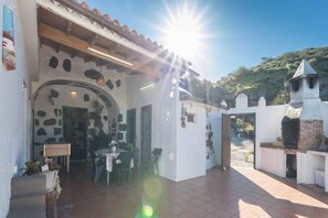 A building with a patio area, a table with chairs, and a small garden. - Cave Retreat with Private Pool (Artenara)