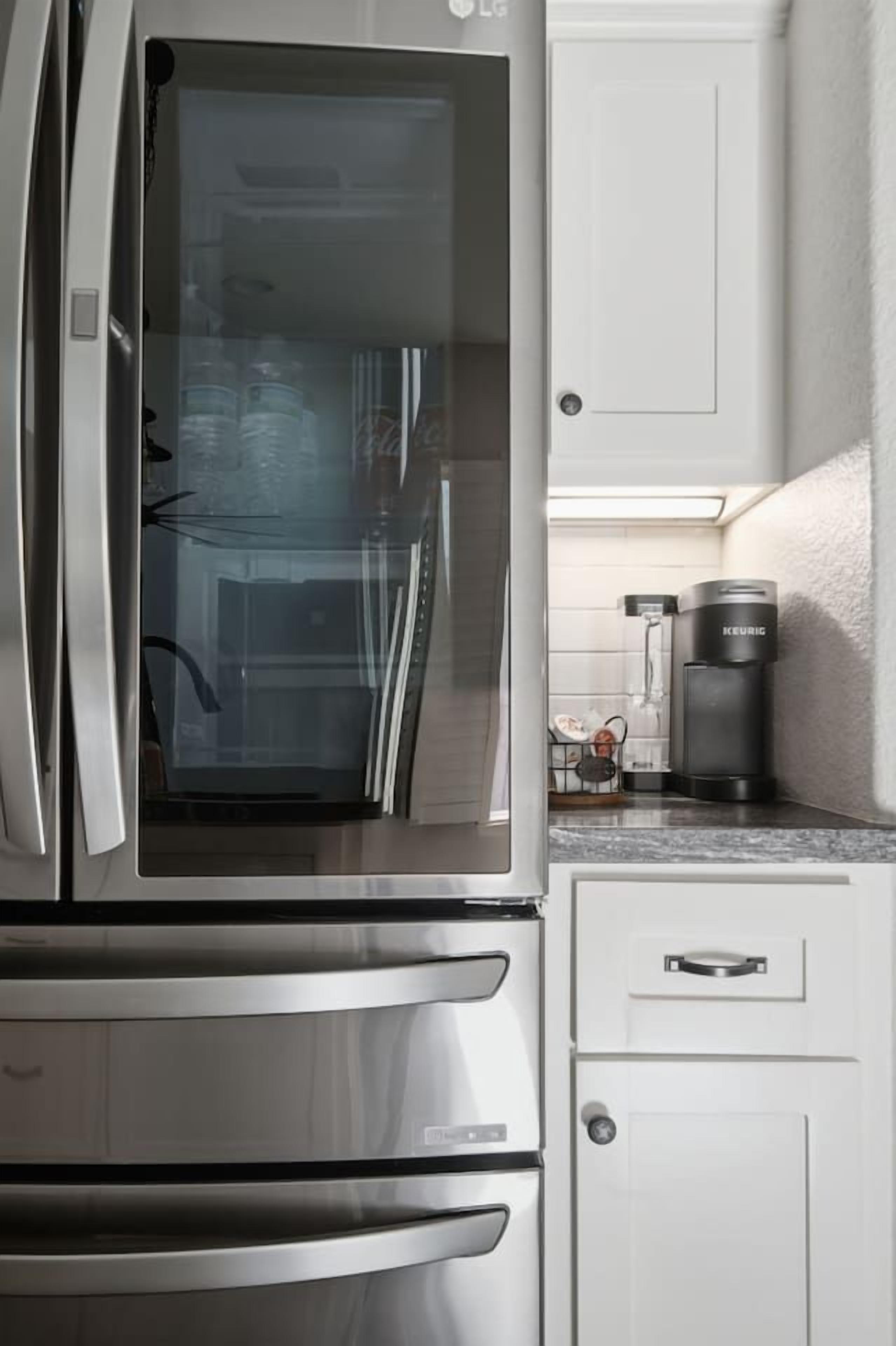 A kitchen with a stainless steel refrigerator, a coffee maker, and a microwave.