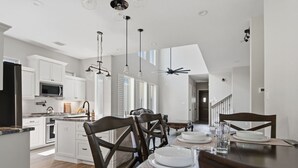 Een moderne keuken met witte kasten, een centraal eiland en hangende lampen.
