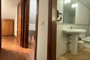A hallway with wooden flooring leading to a bathroom with a white sink and a toilet. - Apartment for Couples in Valleseco (Valleseco)