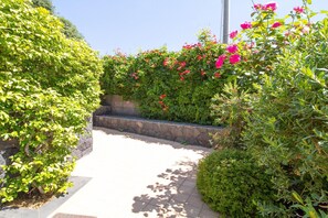 A pathway flanked by lush green hedges and flowering plants. - Garden Apartment for 5 Guests (Trecastagn)