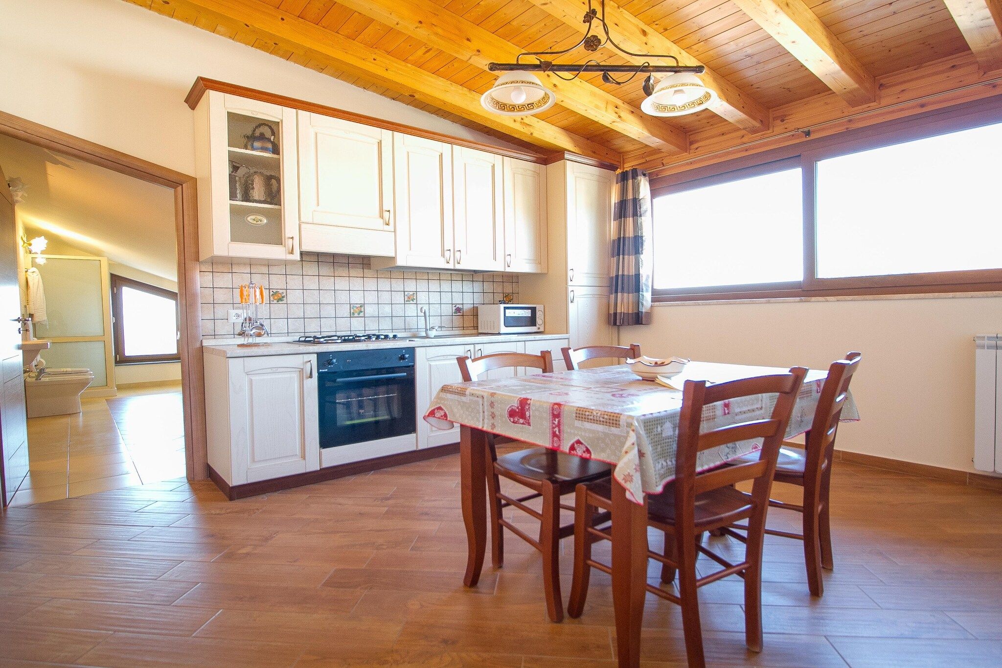 A kitchen with wooden cabinets, a dining table with chairs, and a window providing natural light.