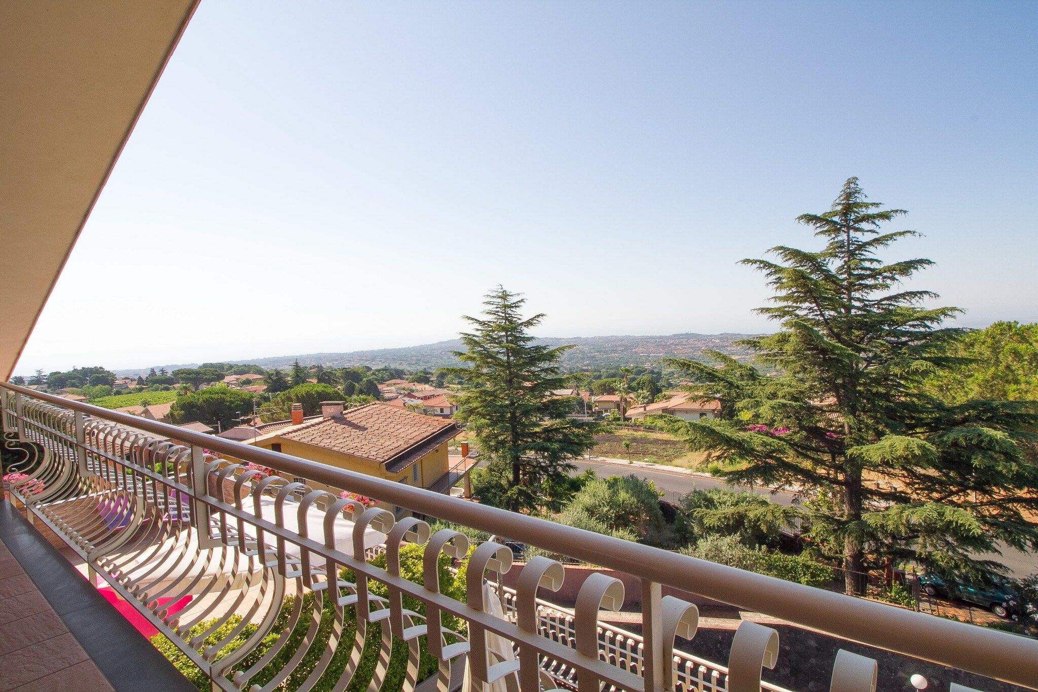 Ein Balkon mit Blick auf eine Wohngegend, mit Häusern und Bäumen.