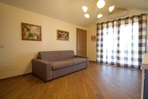 A room with a sofa, wooden flooring, a door, and a checkered curtain. - Beautiful Sea-View Attic Suite (Trecastagn)
