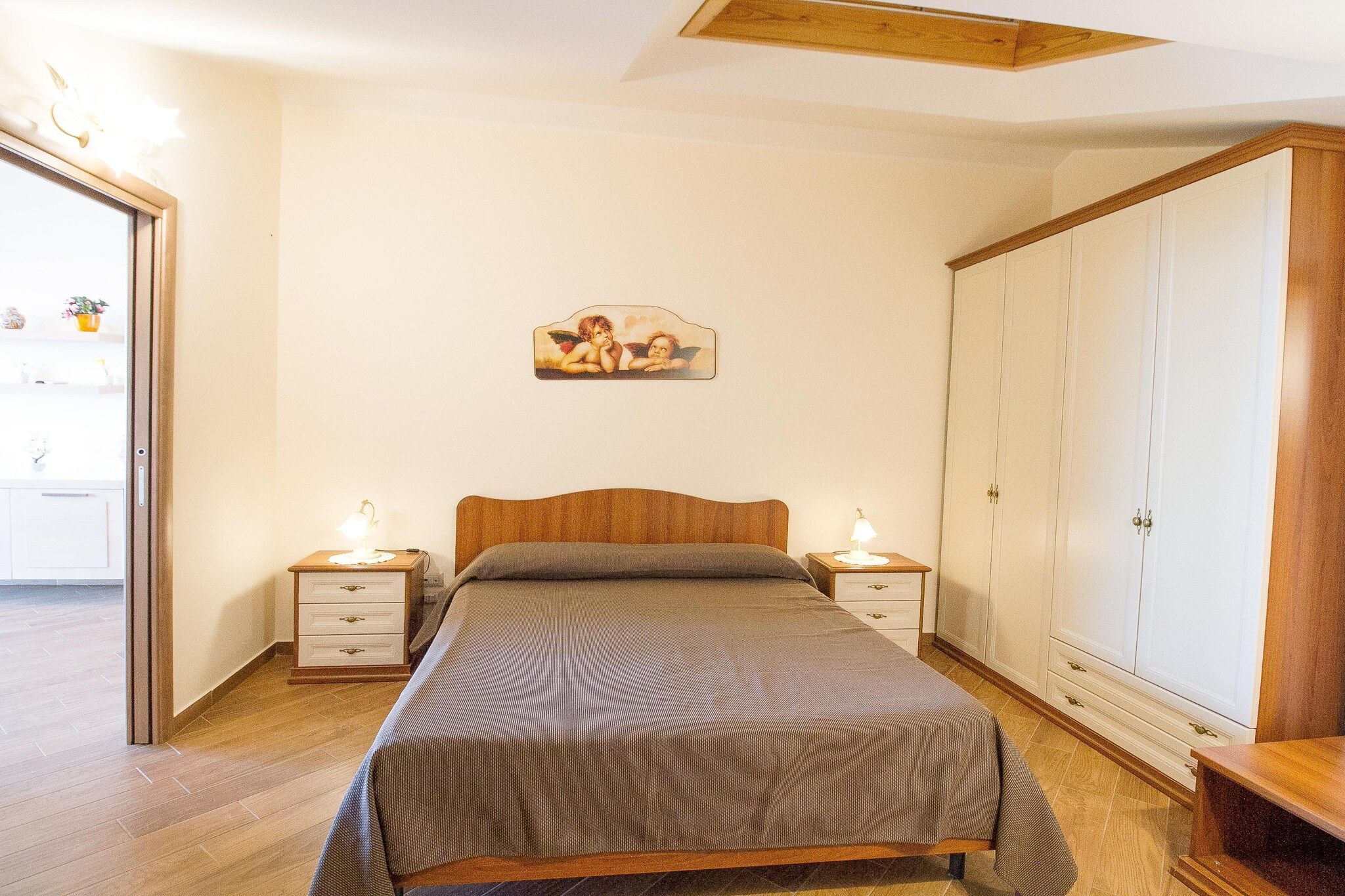 Une chambre à coucher comprenant un lit, des tables de chevet, une armoire et un tableau accroché au mur.