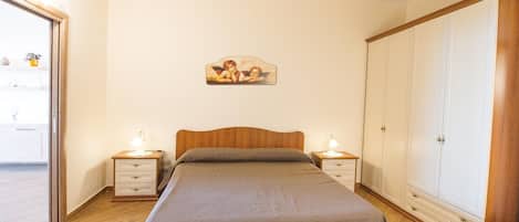 A bedroom with a bed, bedside tables, a wardrobe, and a wall-mounted picture.