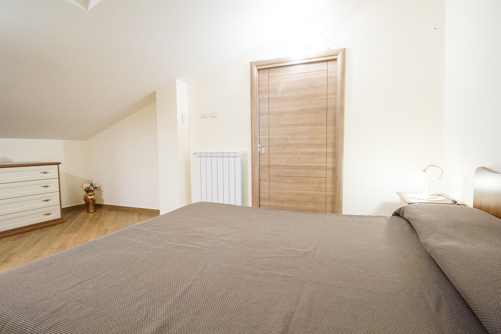 Ein Schlafzimmer mit einem Bett, einem Schminktisch, einem Heizkörper und einer Tür.