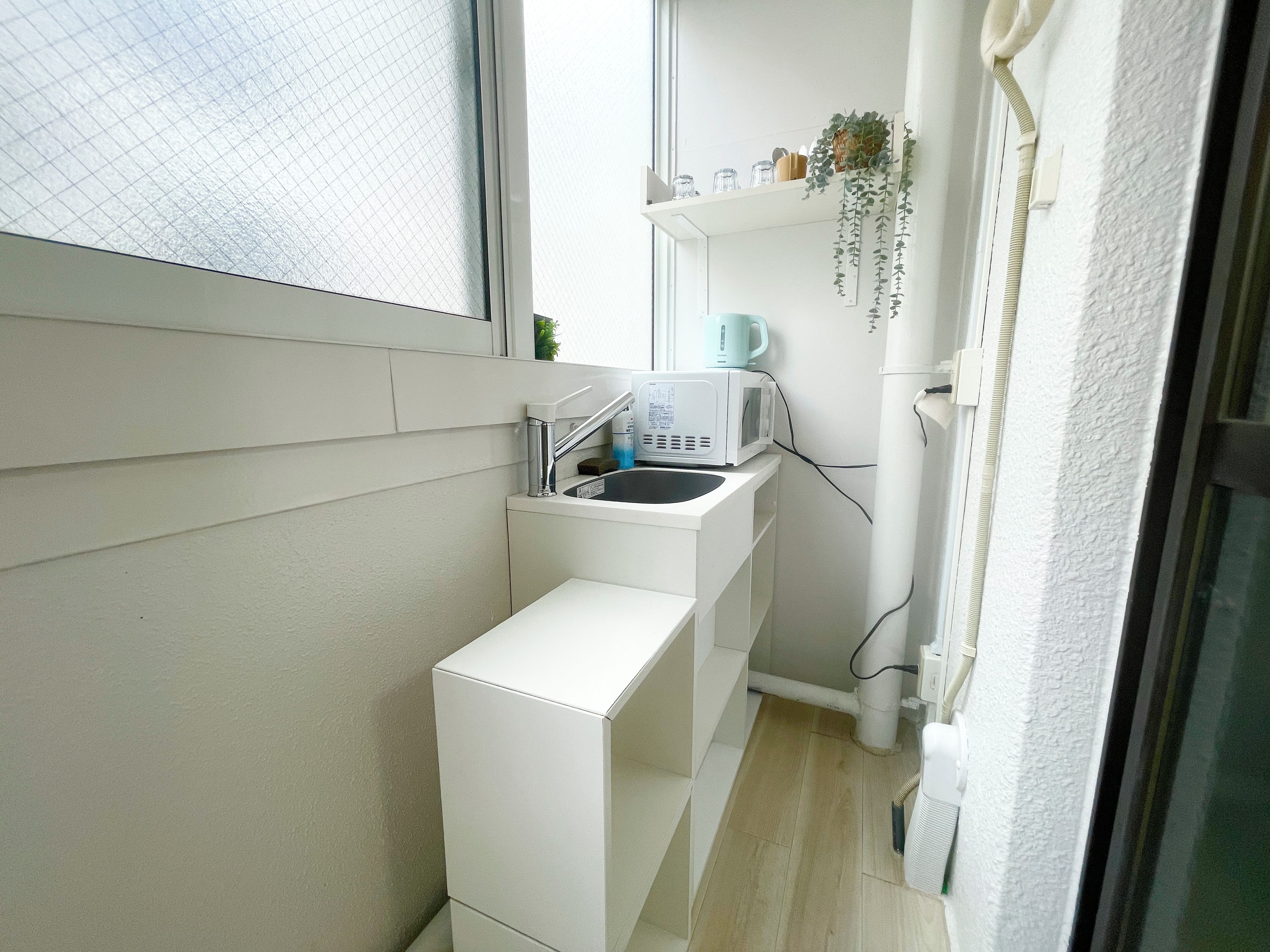 A compact kitchen with a microwave, sink, and a small window.