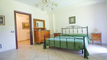 A bedroom with a bed, dresser, and a chandelier.