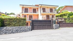 A multi-story residential building with a gated entrance, stone wall, and a clear sky. - Spacious Sicilian Etna Villa (Trecastagni CT)