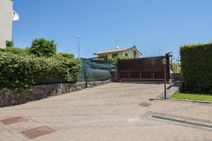 A paved driveway leading to a gated entrance with a house in the background.