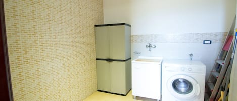 Una lavanderia funzionale con lavatrice, lavandino e pensile.