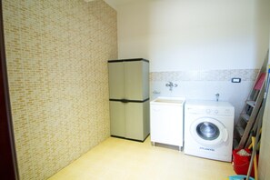 A compact laundry room with a washing machine, a sink, and a cabinet.