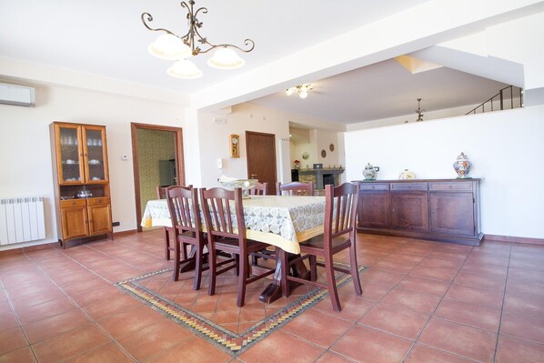 A dining area with a table set for four, surrounded by chairs. There is a cabinet with glass doors and a radiator on the wall.