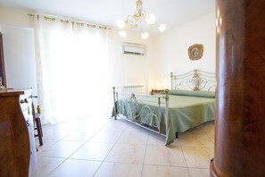 A bedroom with a bed, a radiator, a chandelier, and a picture on the wall. - Spacious Sicilian Etna Villa (Trecastagni CT)