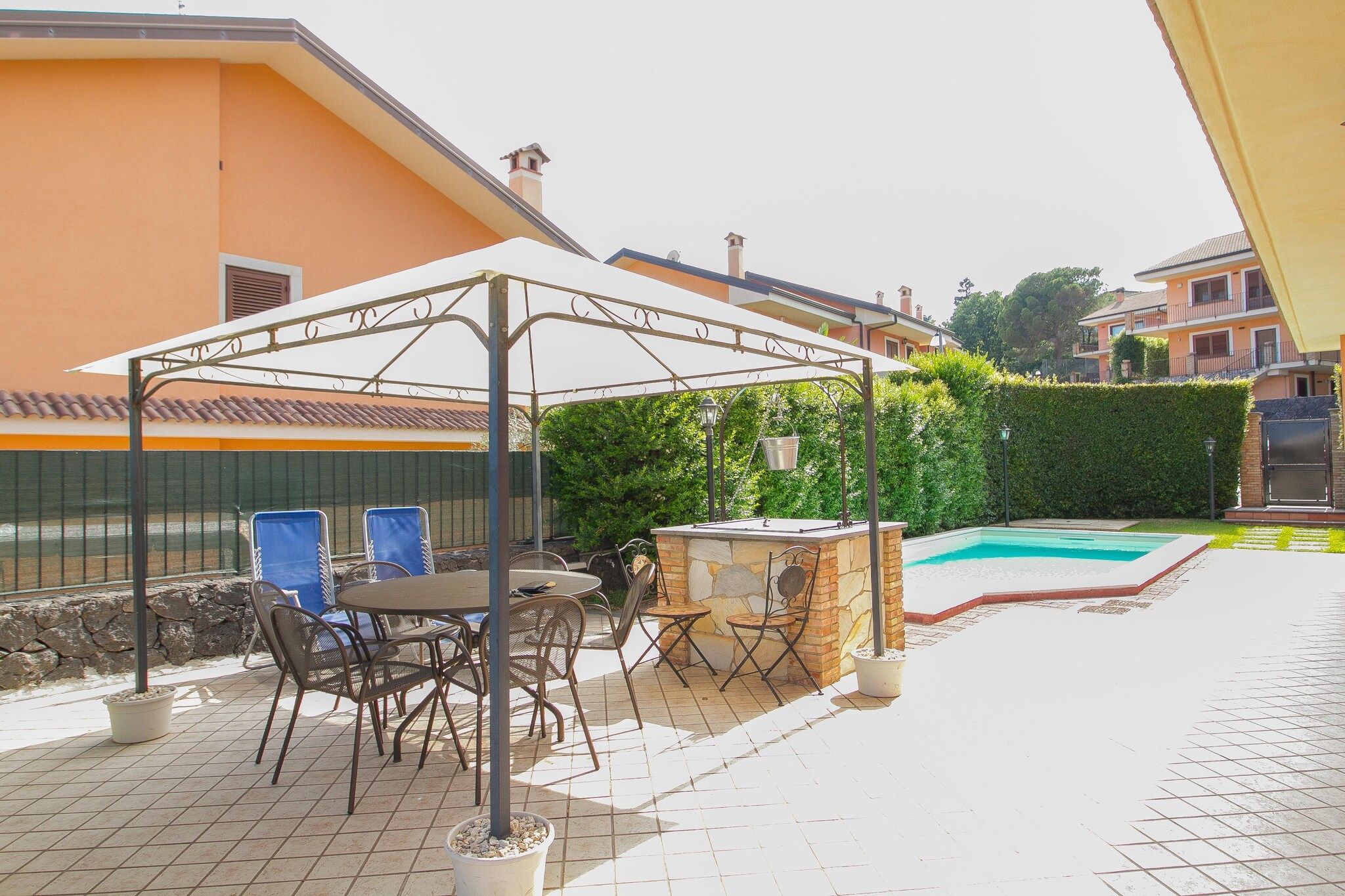 An outdoor patio with a covered seating area, a pool, and a stone wall.