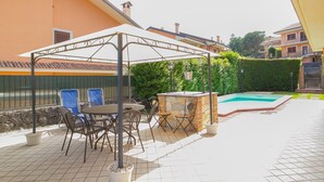 An outdoor patio with a covered seating area, a pool, and a stone wall. - Spacious Sicilian Etna Villa (Trecastagni CT)