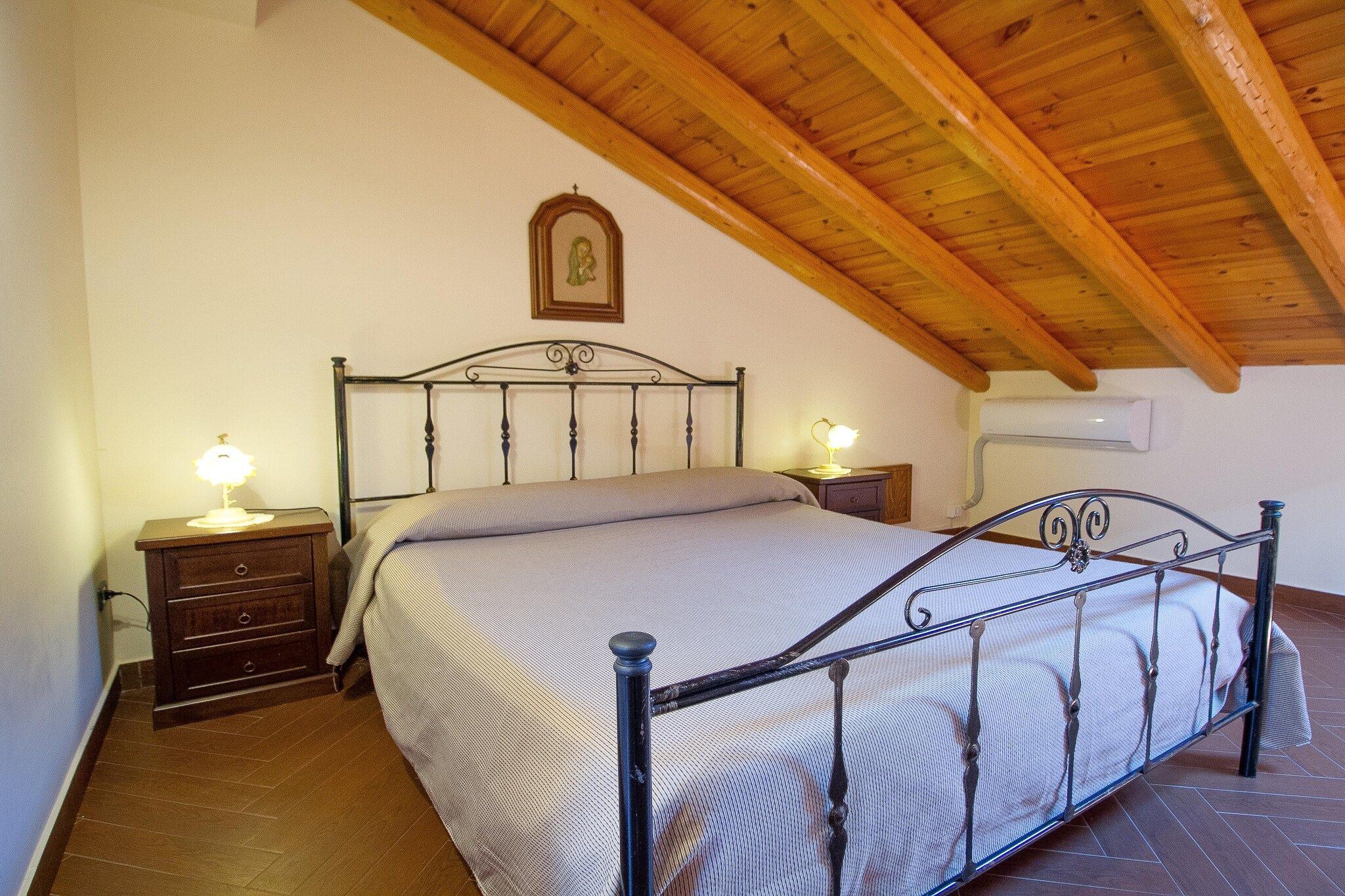 A bedroom with a bed, nightstands, and a wooden ceiling.
