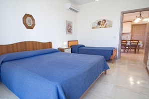 A hotel room with two beds, a small table, a chair, and a dining area with a table and chairs. - Sea-View Etna Residence (Trecastagn)
