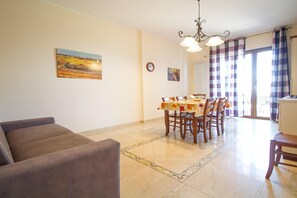 A dining area with a table set for four, surrounded by chairs, a sofa, and a decorative rug. - Sea-View Etna Residence (Trecastagn)