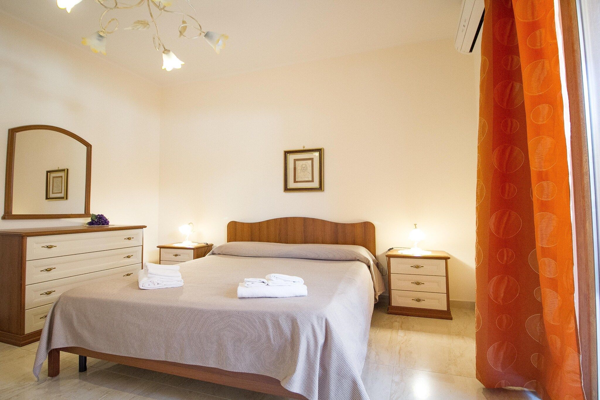 Ein Schlafzimmer mit einem Bett, zwei Nachttischen, einem Schminktisch und einem Spiegel.