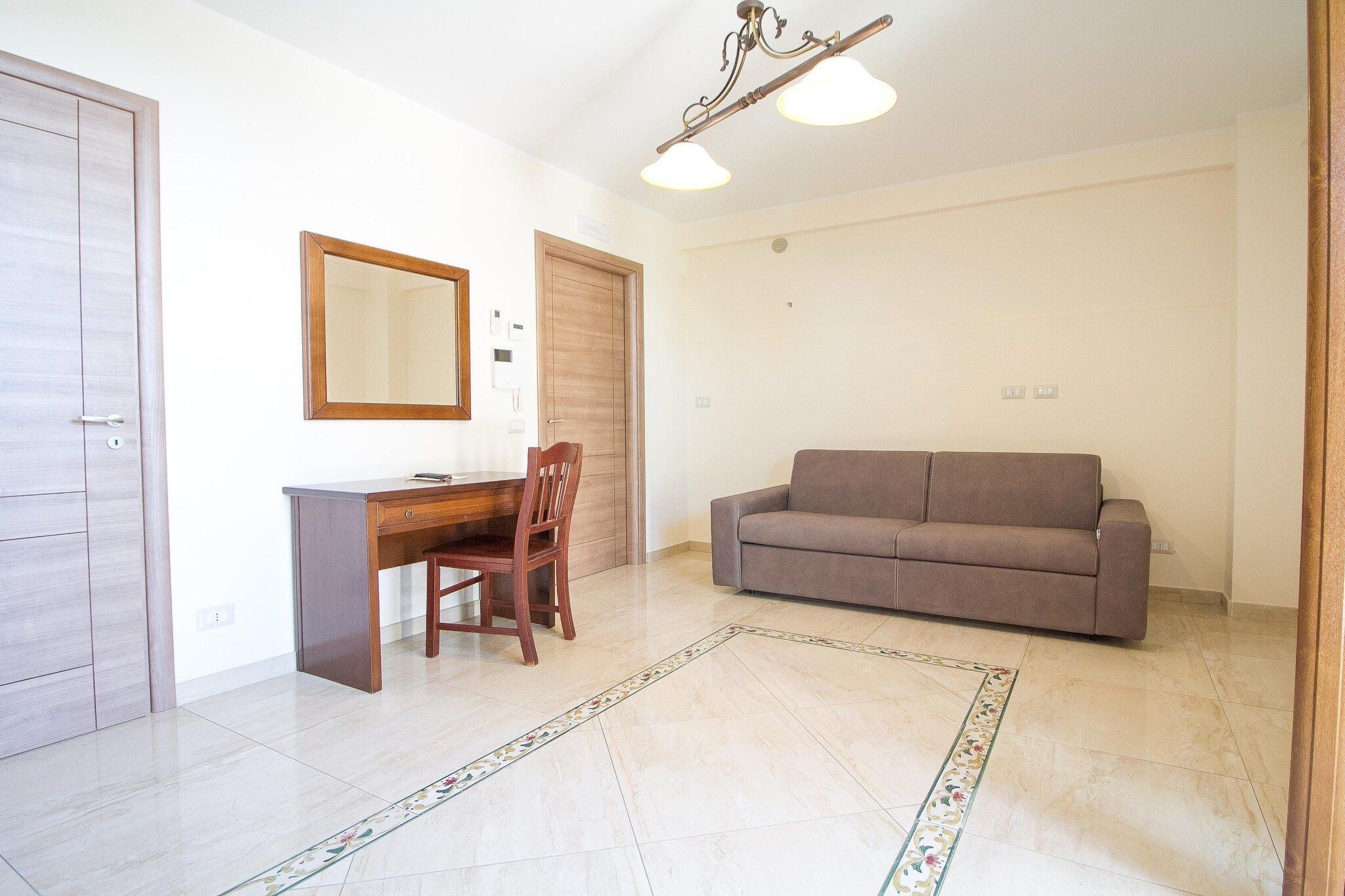 Ein Zimmer mit Schreibtisch, Stuhl, Sofa und einem dekorativen Teppich.