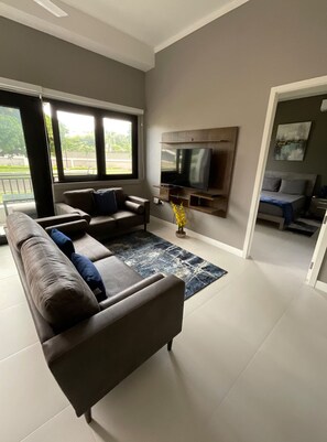 A modern living room with a sofa, TV, and a dining area. - VIA Braemar Apartment with rooftop pool  (Kingston)