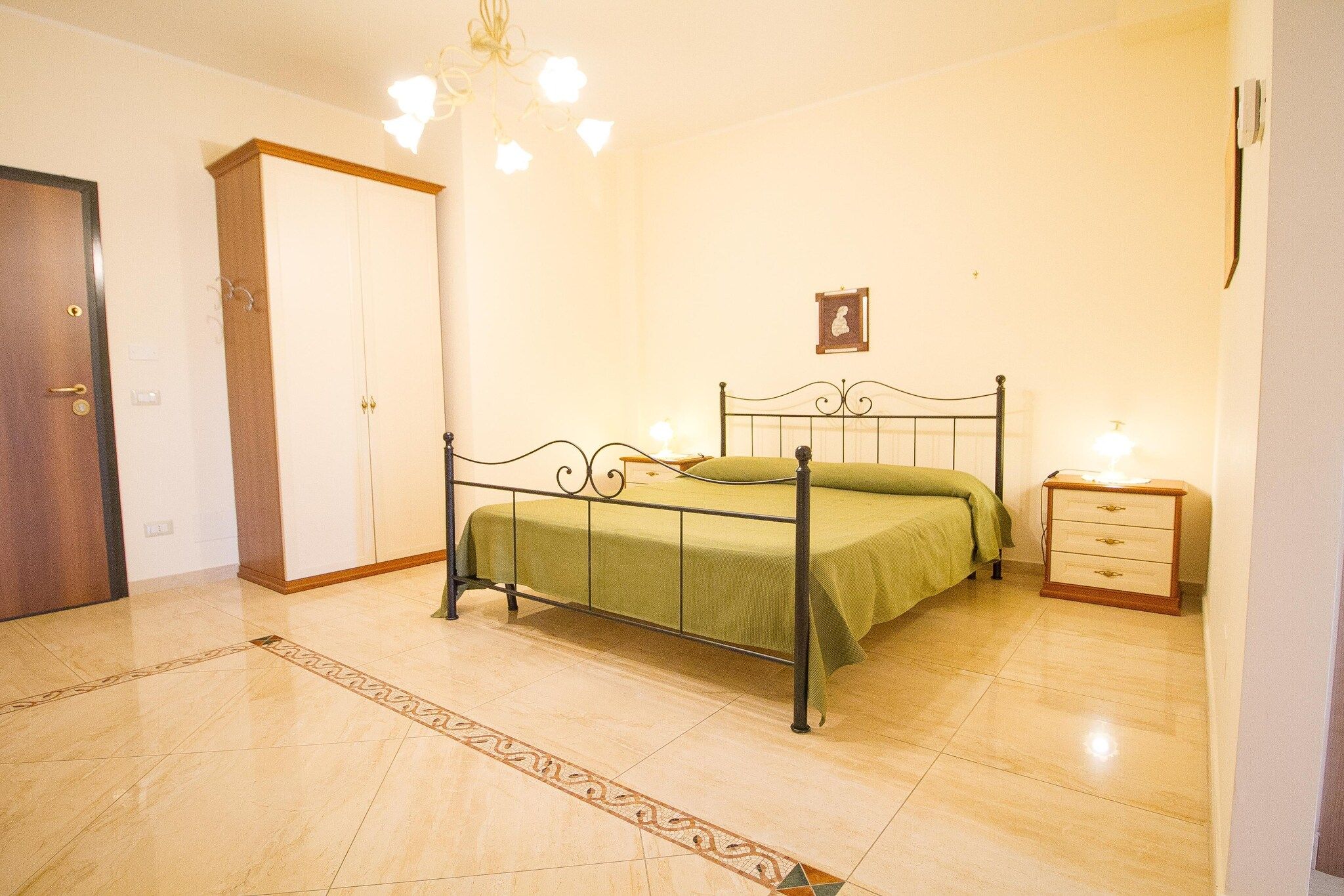 Une chambre à coucher comprenant un lit, une table de chevet, une armoire et un lustre.