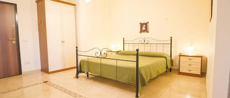 A bedroom with a bed, a nightstand, a wardrobe, and a chandelier.