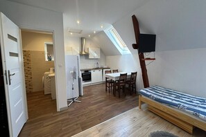 Un appartement compact comprenant un coin cuisine, un espace repas et un coin nuit avec un lit.