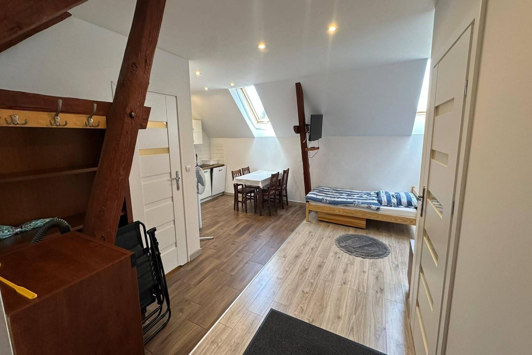 A compact room with a loft bed, a dining table, and a small kitchen area.