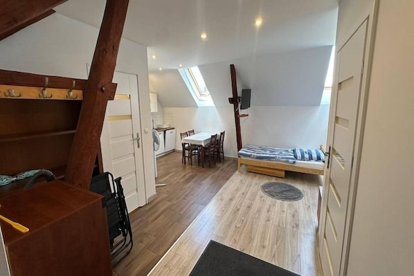 Une pièce de style loft avec un plafond en pente, un lit, un coin repas et un fauteuil roulant.