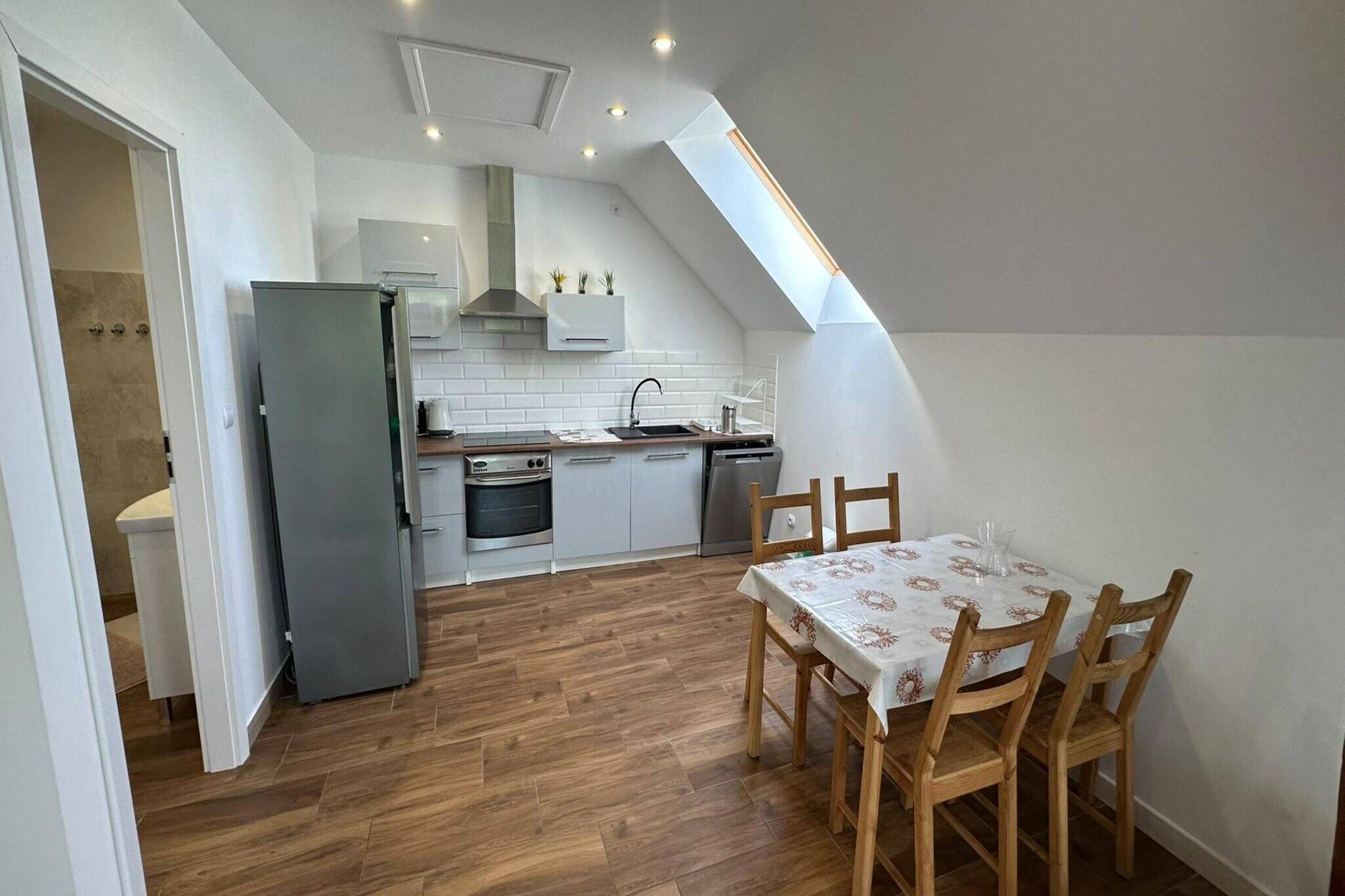 Une cuisine compacte avec un coin repas, comprenant une table et des chaises en bois, un four encastré et un petit évier.