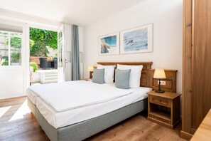 A hotel room with a large bed, two bedside tables with lamps, a wooden wardrobe, and two framed pictures on the wall. - Aparthotel An Sankt Marien (Stralsund)