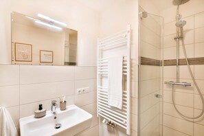 A bathroom with a sink, mirror, towel rack, and shower. - Aparthotel An Sankt Marien (Stralsund)