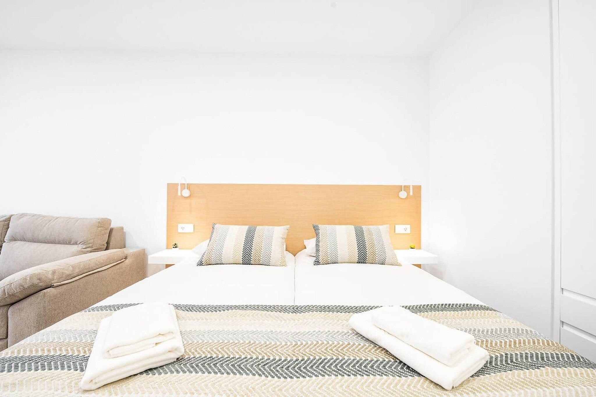 Ein Hotelzimmer mit einem Bett, zwei Nachttischen, einem Sessel und einem Teppich mit Muster.