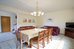 Ein Essbereich mit Tisch, Stühlen, einer Chandelier und einem Fernseher.