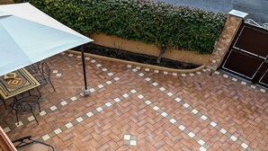 A patio area with a tiled floor, outdoor furniture, and a hedge. - Family Sicilian Heritage Home (TRECASTAGNI)