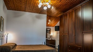 A bedroom with a bed, wooden wardrobe, and a ceiling light fixture. - Family Sicilian Heritage Home (TRECASTAGNI)