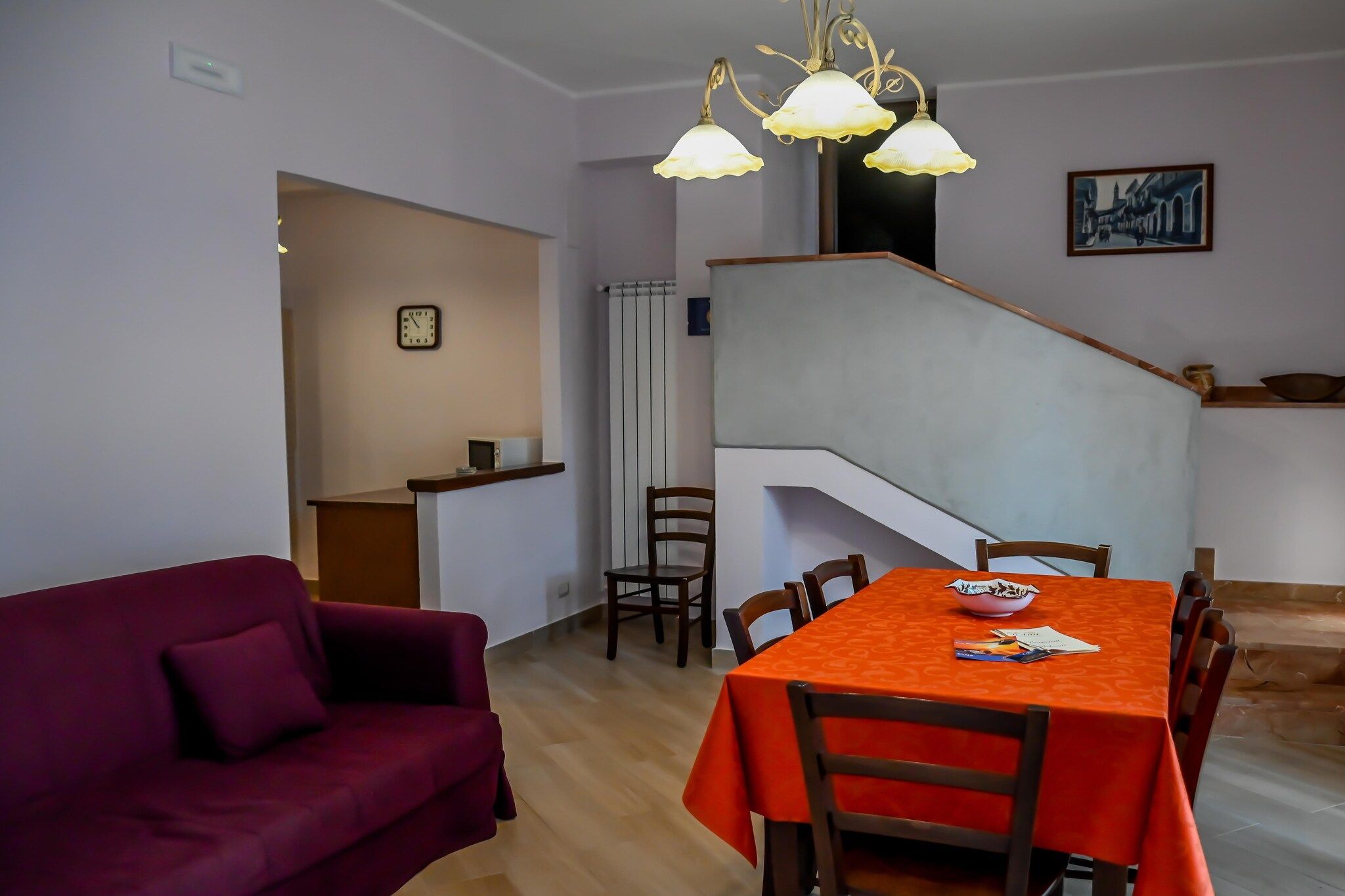 A dining area with a table set for four, a staircase, and a living room with a sofa.