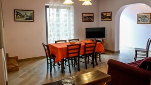A dining area with a table set for four, a television, and framed pictures on the walls. - Family Sicilian Heritage Home (TRECASTAGNI)