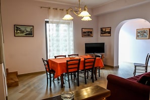 A dining area with a table set for four, a television, and framed pictures on the walls.