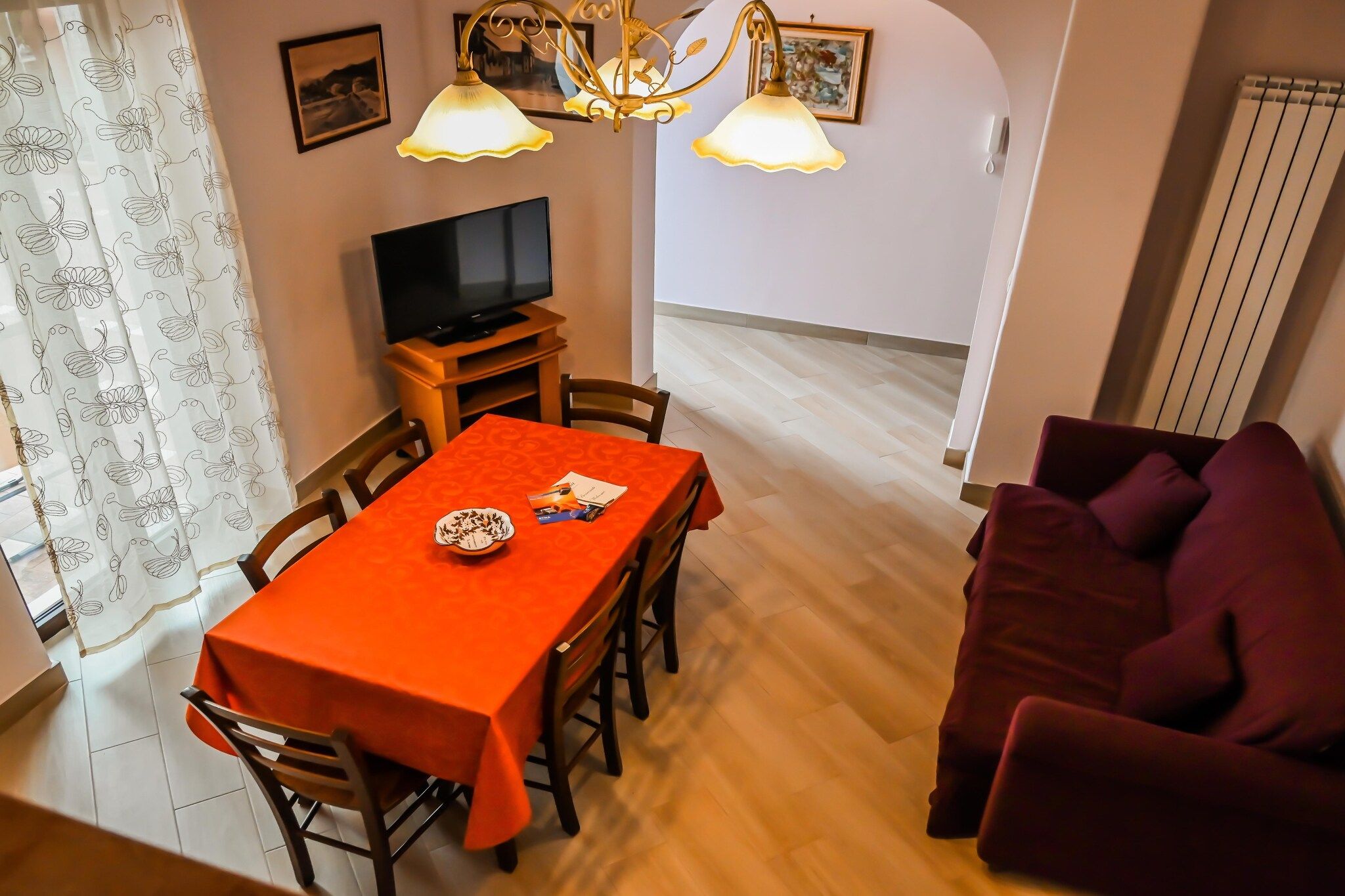 Ruokailutila, jossa on pöytä, tuoleja, televisio ja sohva.