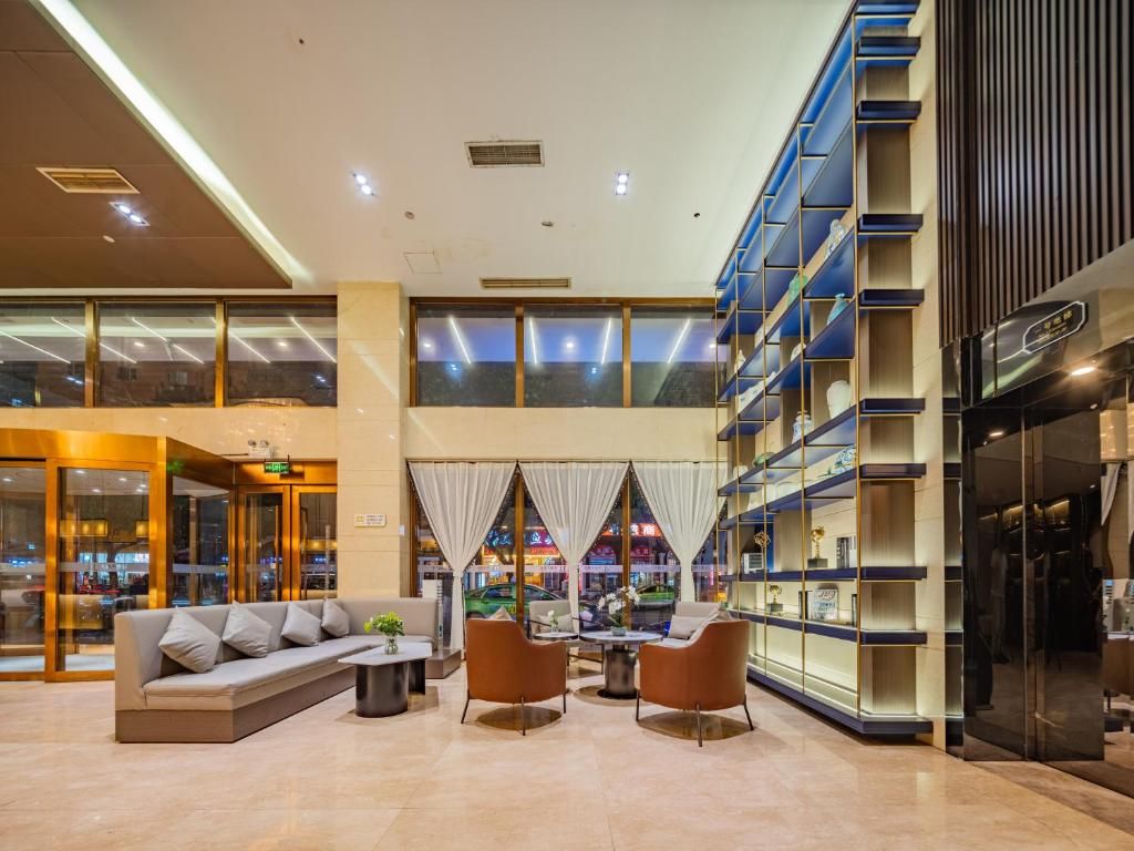A modern lobby with a seating area, a staircase, and a glass facade.