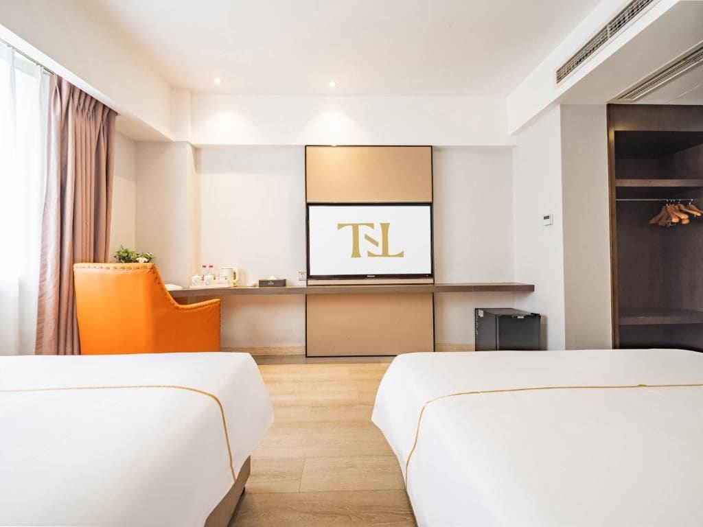 Une chambre d’hôtel avec deux lits, un bureau, une télévision et une armoire.