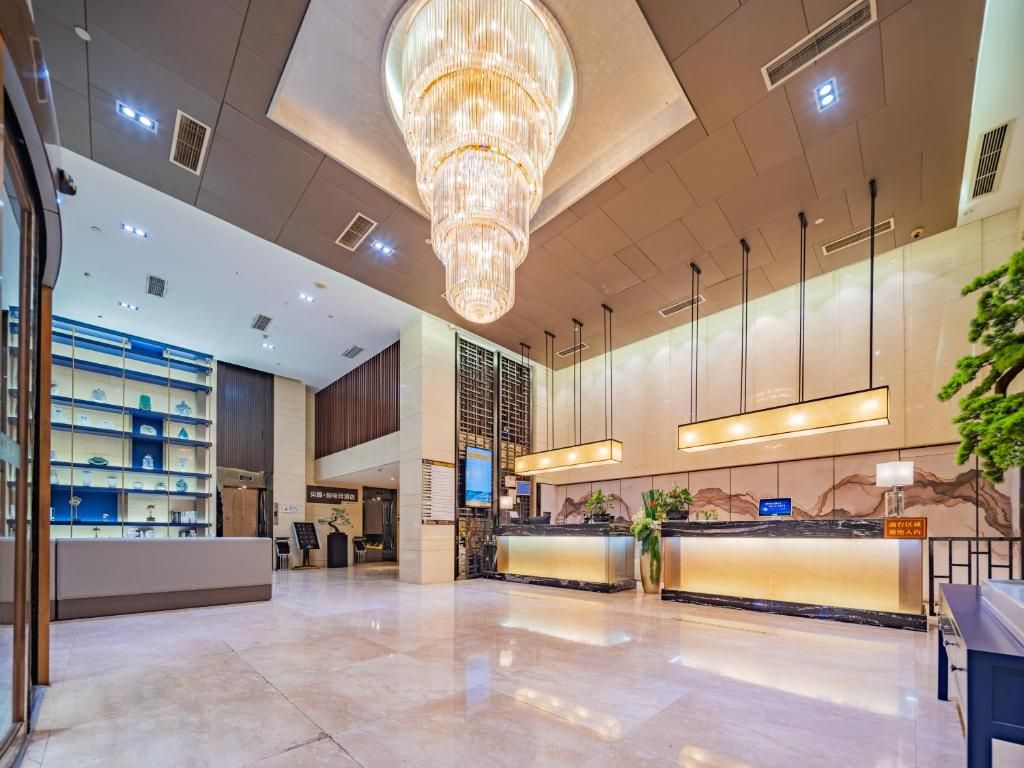 Un moderno vestíbulo de hotel con una recepción, una araña y un ventanal grande.