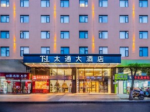 Un hotel con un letrero grande, múltiples ventanas y una fachada con diversas tiendas.