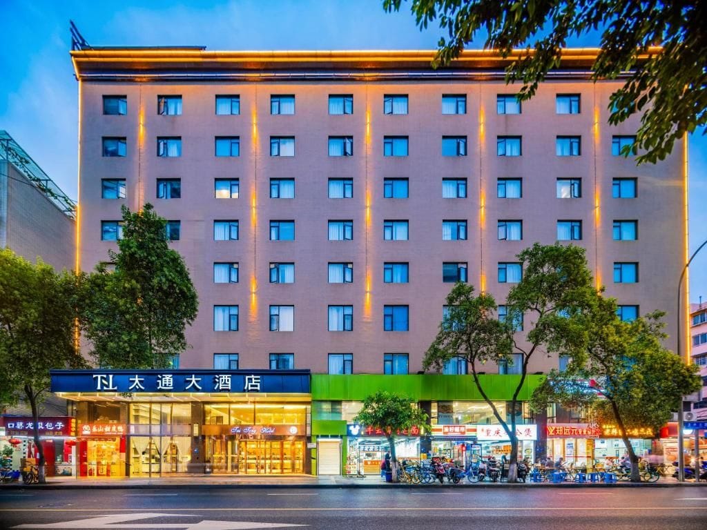 Un hotel de varios pisos con una fila de ventanas en cada planta, una entrada a nivel de suelo con un letrero y un toldo verde sobre la entrada.