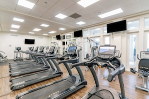 A gym with multiple treadmills, exercise bikes, and cardio machines. - 🌴Dune's Perch: Beach Club Resort with Pool + Hot Tub + On-Site Dining (Gulf Shores)