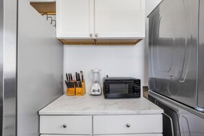A compact kitchen with white cabinets, a microwave, a blender, and a knife block. - 🏖️ Beachfront Salt and Grace: Direct Gulf Access + Balcony + Dog Friendly (Fort Morgan)